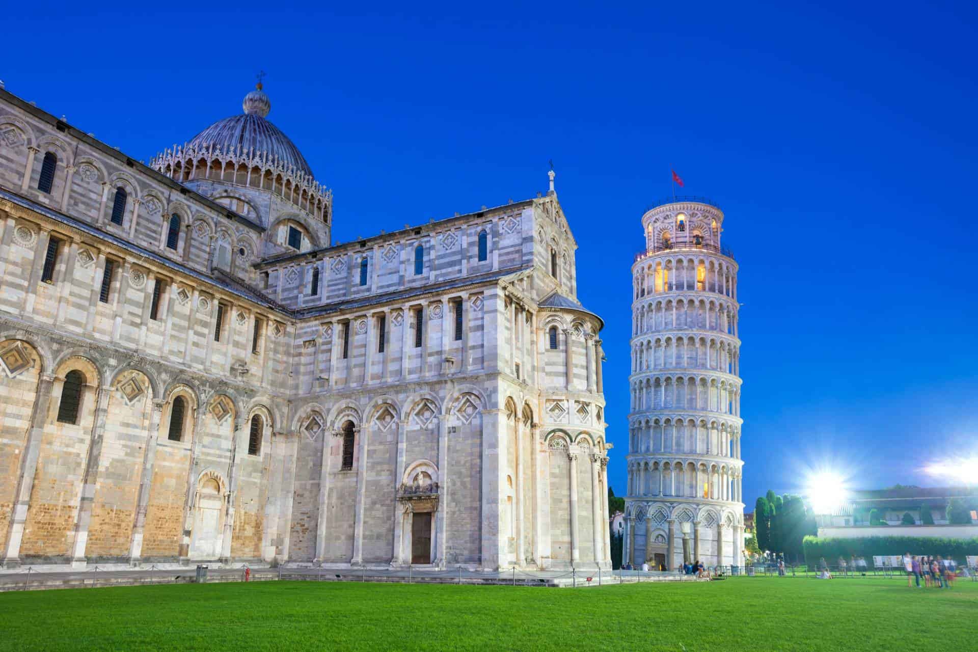 Piazza del Duomo with the leaning tower of Pisa tower and the Cathedral illuminated at night.