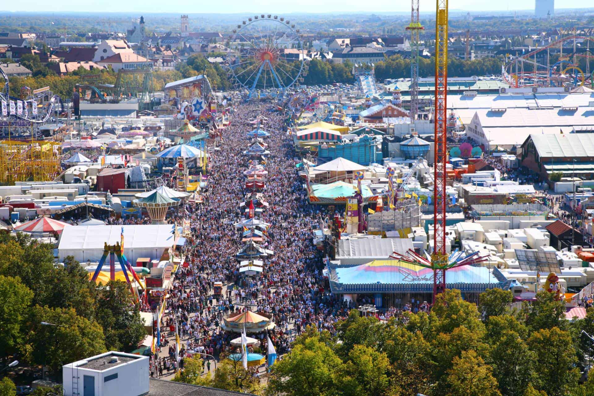 View of huge crowd, park attractions and tents during Oktoberfest in Munich.