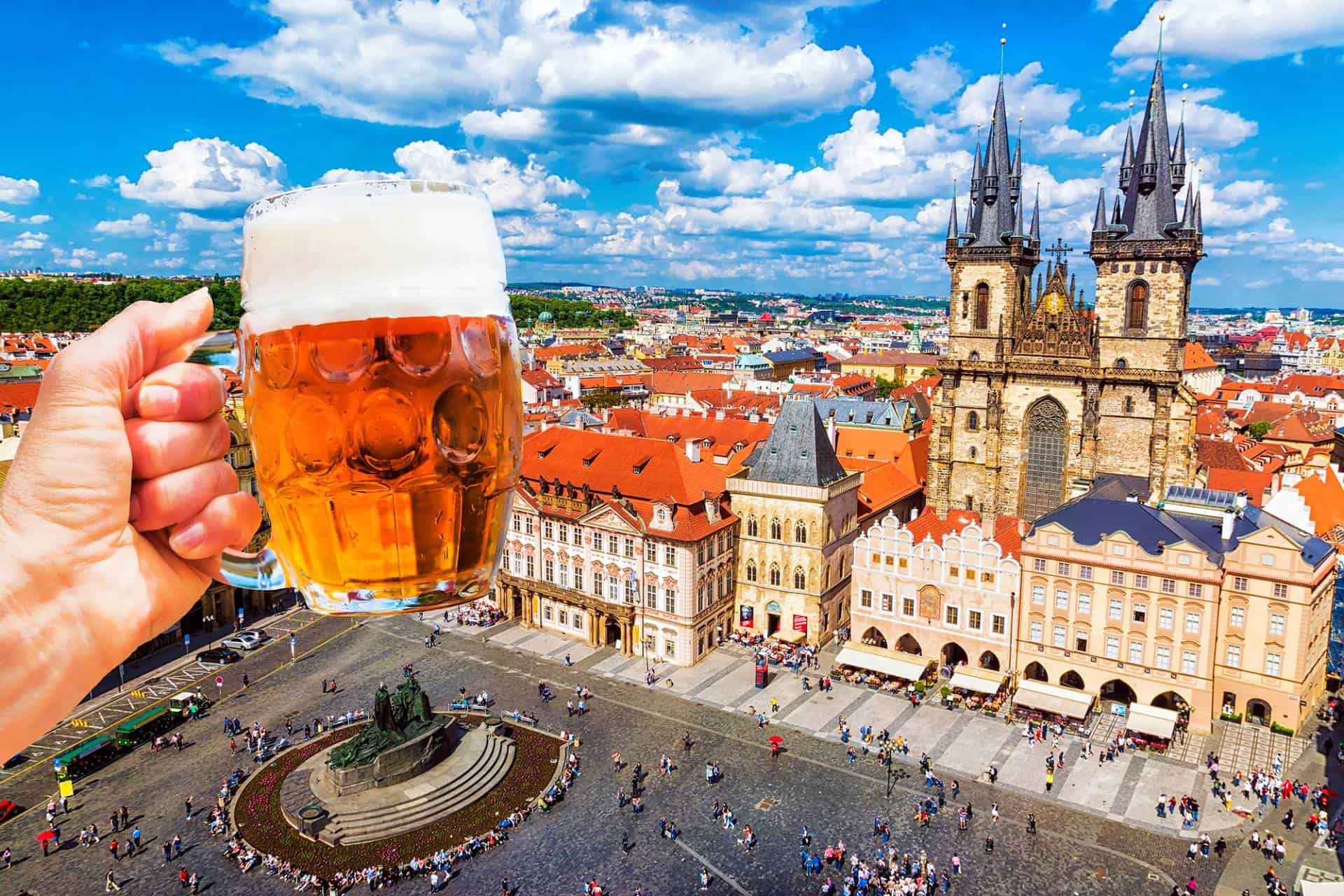 Hand with a mug of beer on the background of the Old Town Square in Prague, Czech Republic.