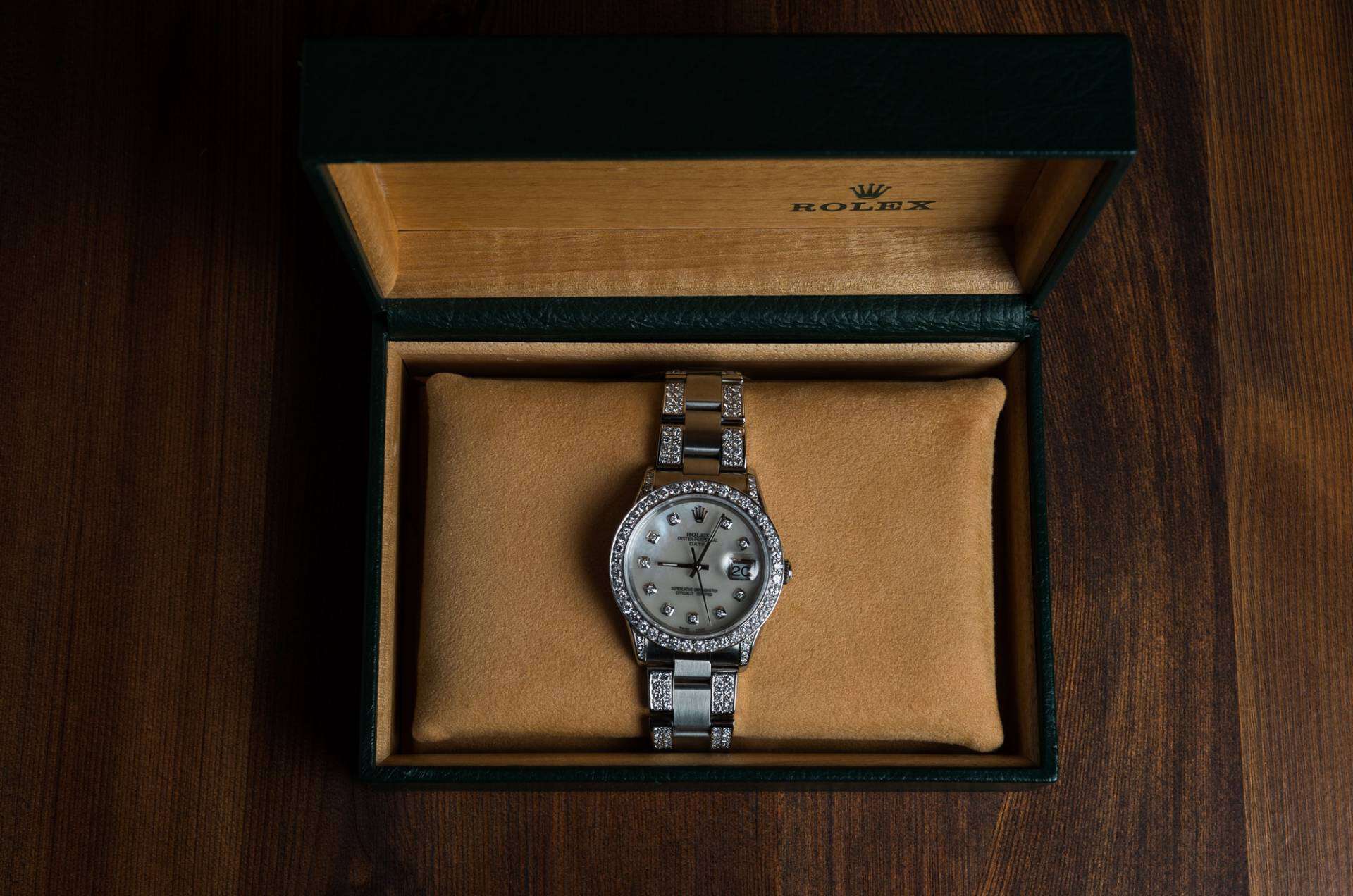 Top view of a Rolex in a green box on a wooden background.