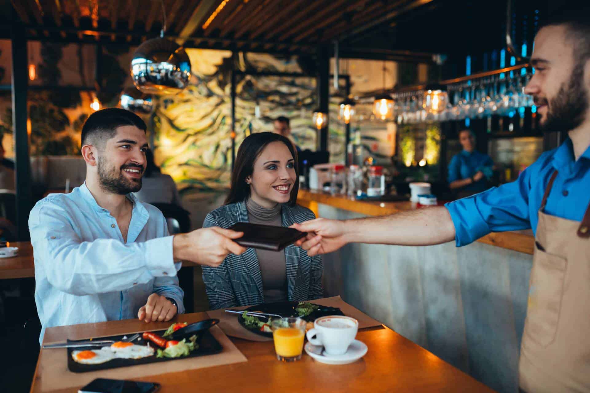 Man with female companion paying bill at a restaurant.