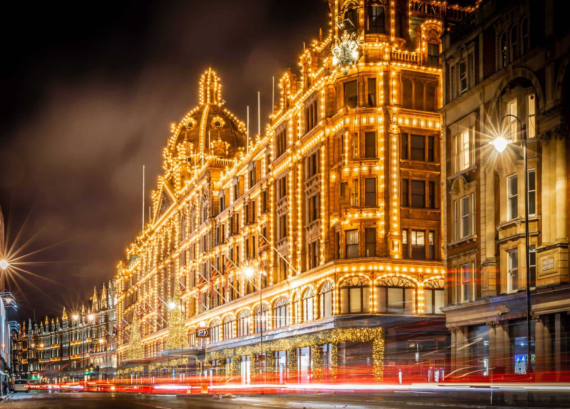 Night traffic in front of Harrods bathed in lights - London’s most famous and iconic luxury department store.