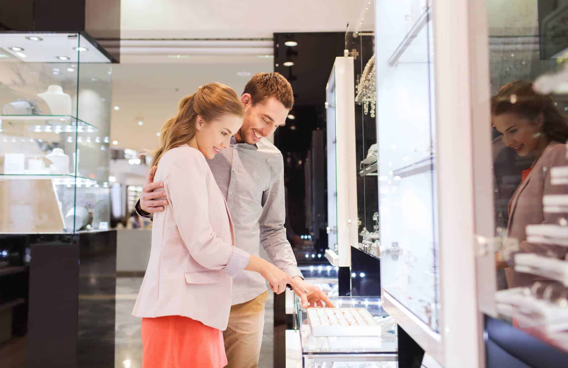 Happy couple choosing engagement ring in jewelry store.