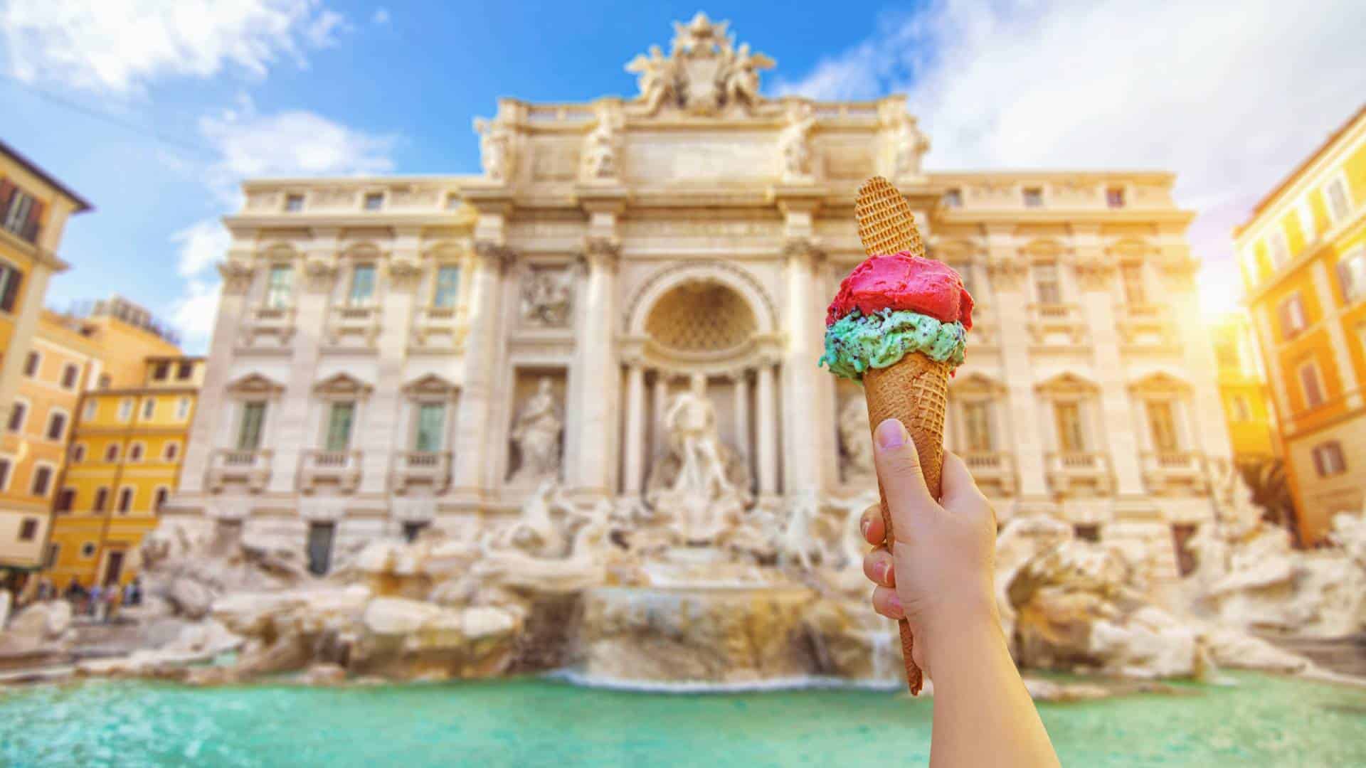Famous landmark Trevi Fountain in Rome Italy on a sunny summer day with cone of Italian gelato in the foreground.