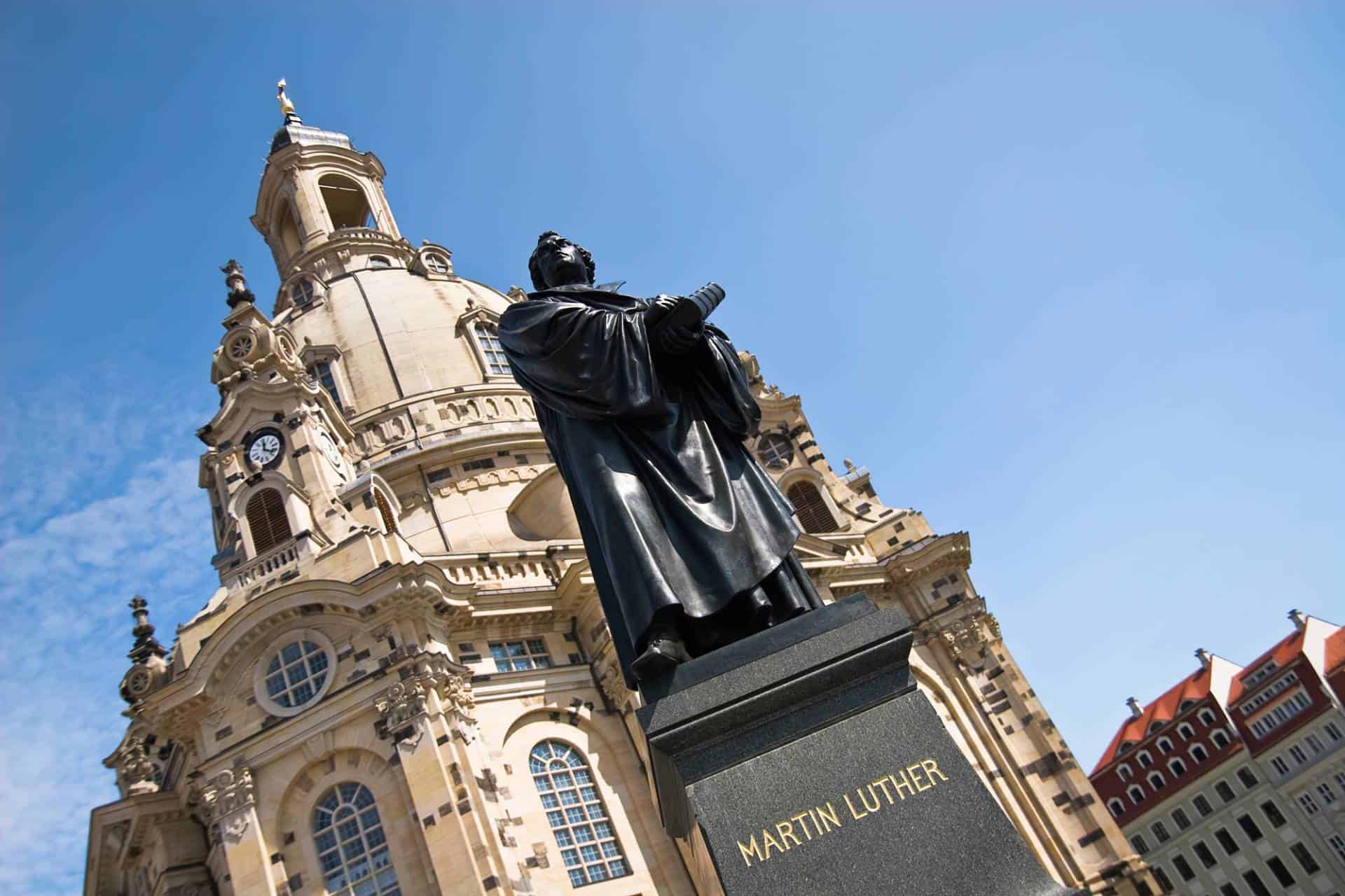 Statue of Martin Luther, the influential figure of the Protestant Reformation, in Dresden, Germany. In the background is the Dresden Frauenkirche, a Lutheran church.