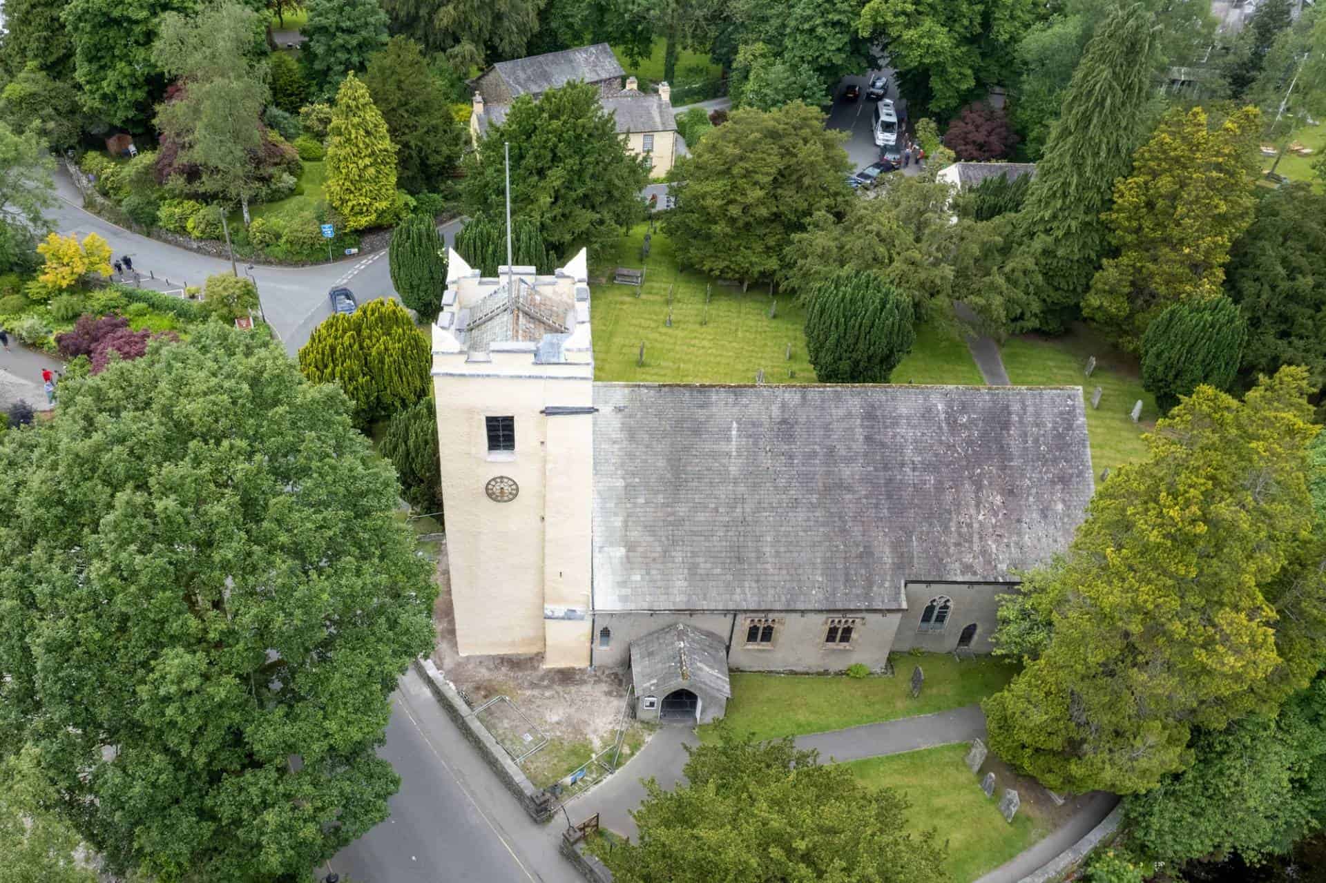 Bird's eye view of St. Oswald's Church surrounded by green trees in Grasmere, England. William Wordsworth is buried inside this church.