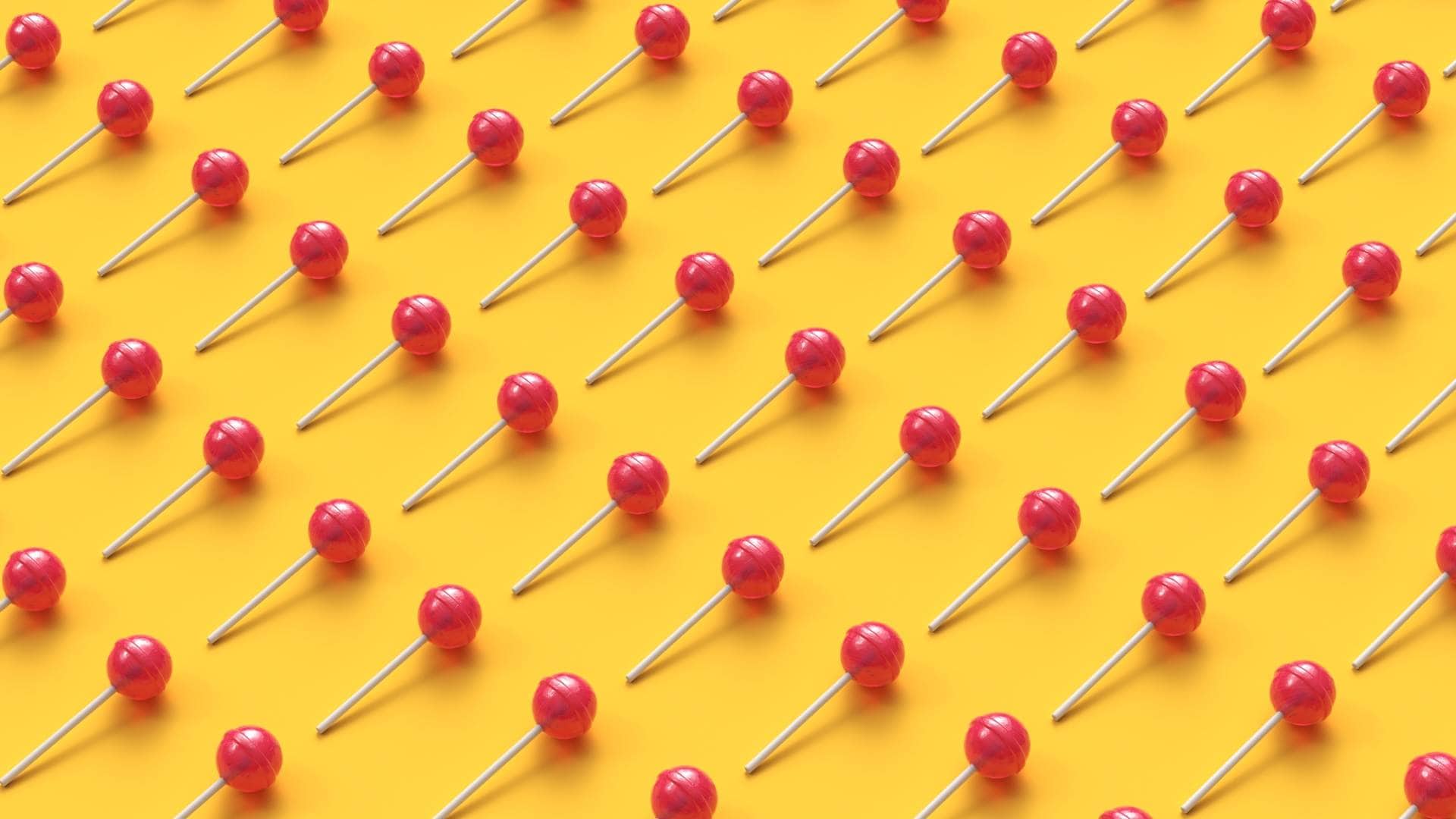 Sweet lollipops arranged in rows on yellow background.