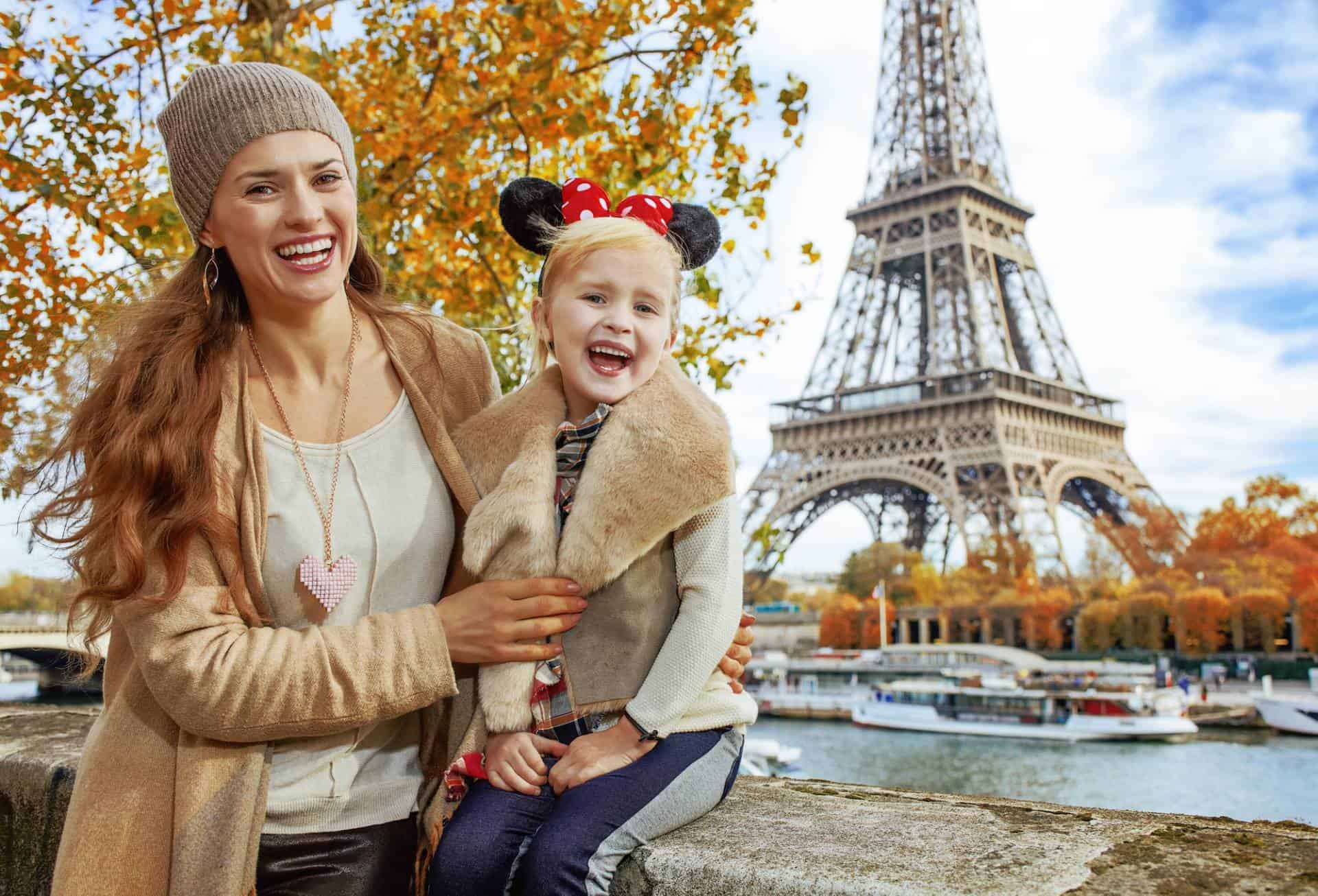 Smiling mother and daughter with Eiffel Tower in the background in autumn, Paris, France.