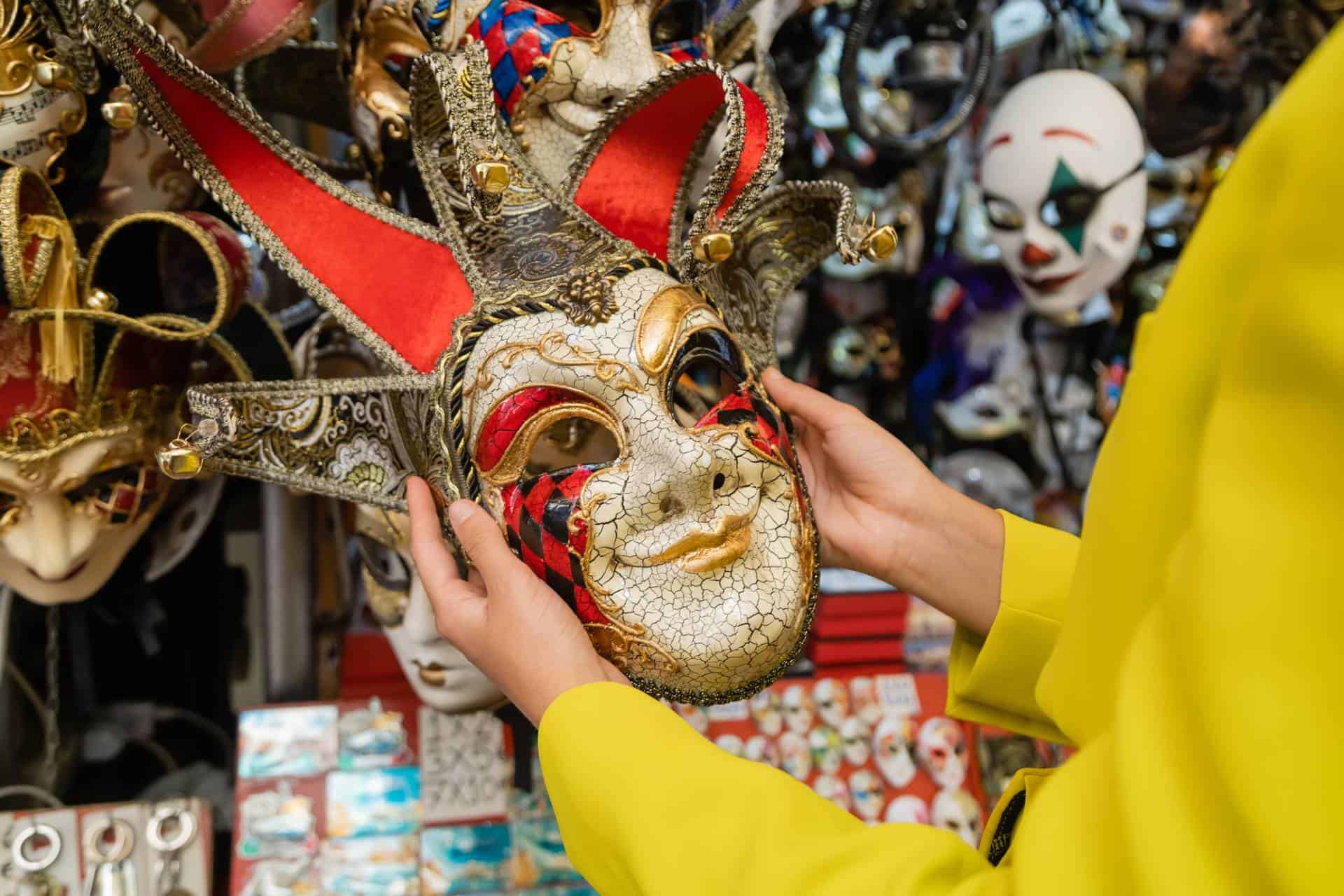 Partial view of woman holding colorful carnival mask in Venice, Italy.