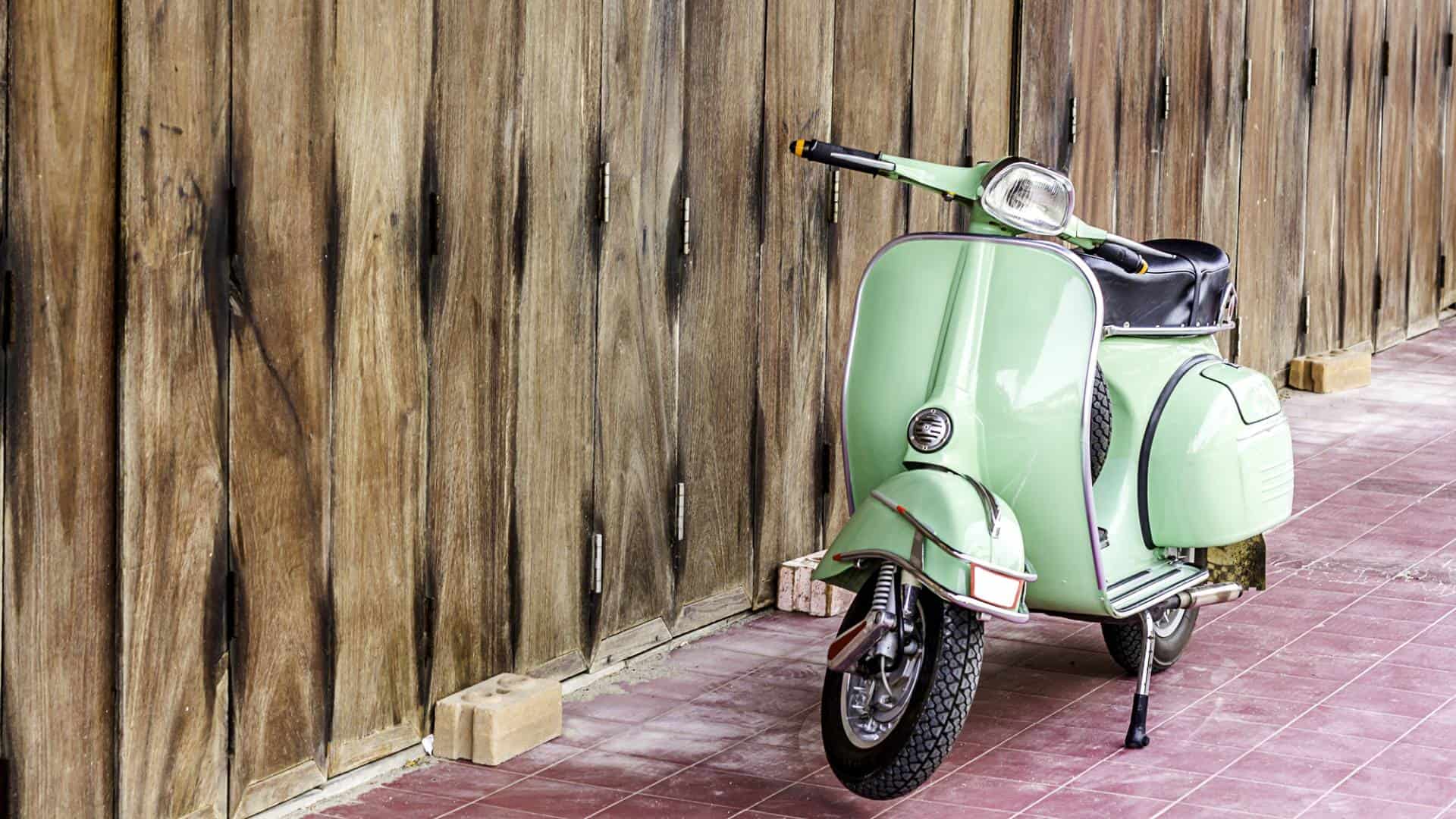 Vintage green Vespa with wooden wall in the background