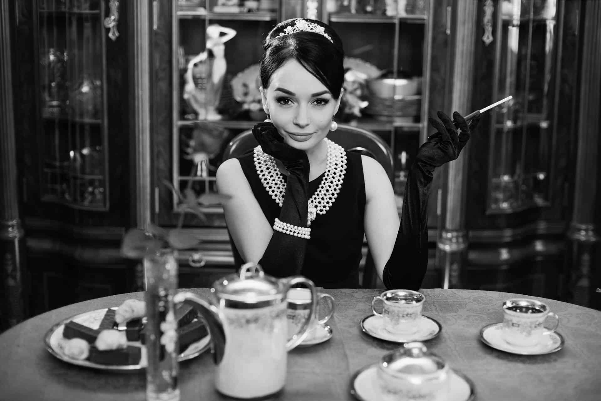 Black and white picture of girl that looks like Audrey Hepburn sitting at the dinner table