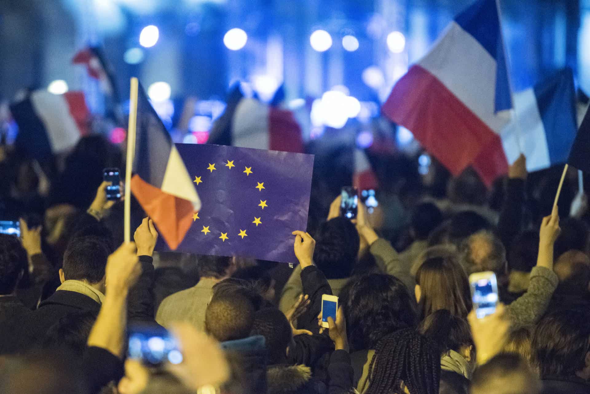 Europe and France flags being waved by crowd at political event in Paris