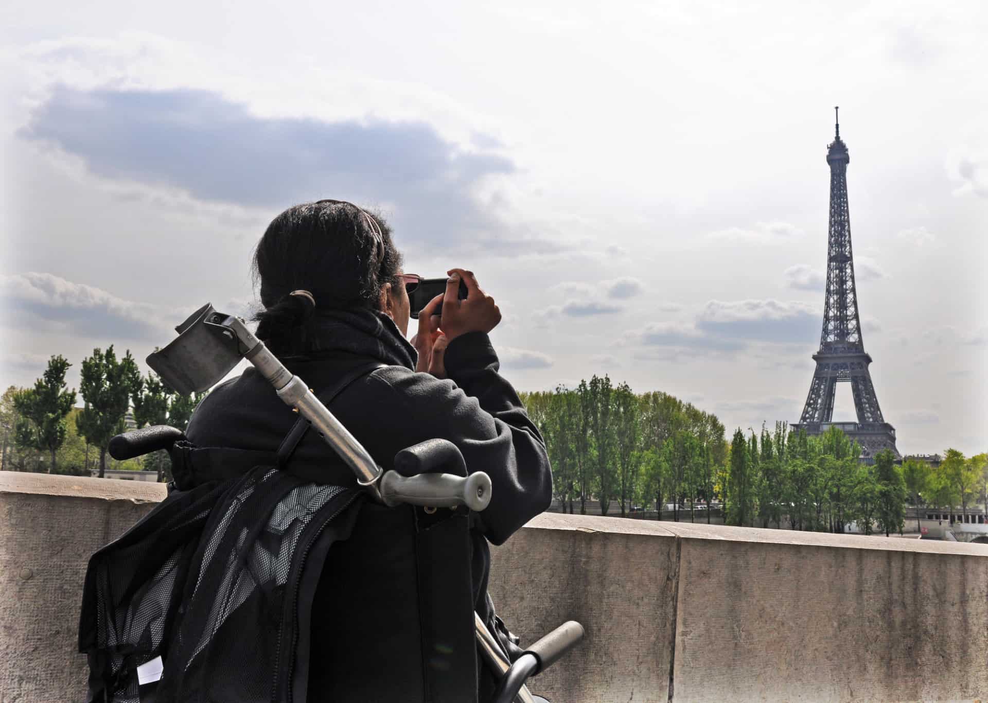 Disabled Traveler in wheelchair taking a picture of the Eifel Tower