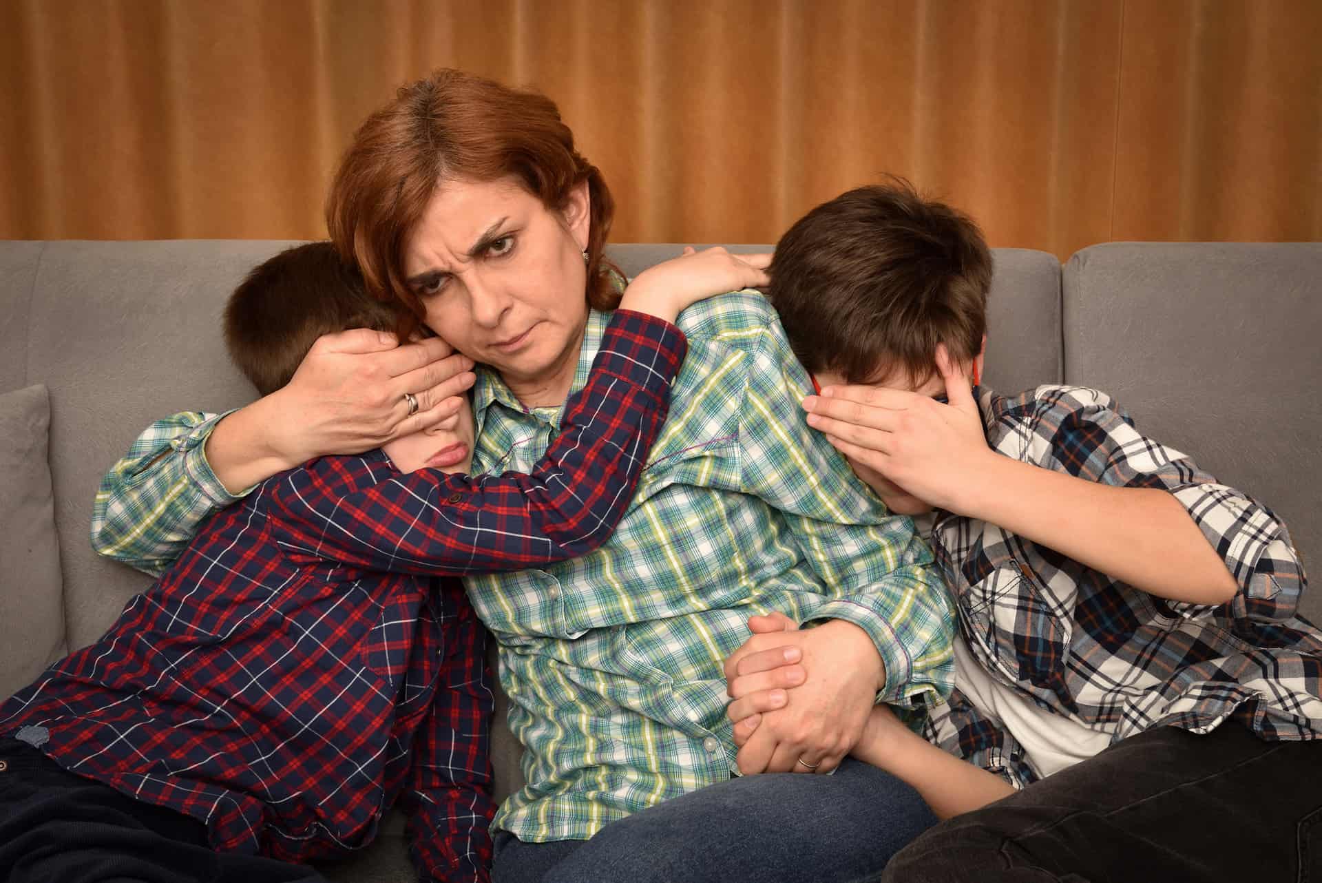 Mother covering kids eyes watching horror on tv